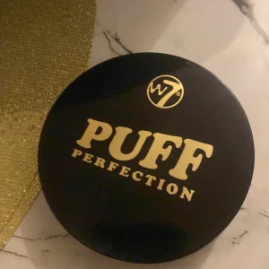 W7 Puff Perfection All in One Cream Powder Compact - Säljer en W7 Puff Perfection All in One Cream Powder Compact i nyansen Translucent. Perfekt för att få en jämn och matt finish. Kompakt och lätt att ta med sig i väskan. Inkluderar en mjuk puff för enkel applicering.