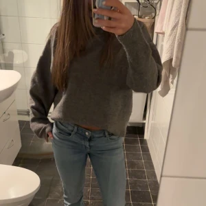 Grå stickad tröja - Mysig grå stickad tröja i oversized passform. Perfekt för kyliga dagar med långa ärmar och en enkel design. Passar bra till jeans för en avslappnad look.