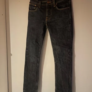 Marinblå jeans från Nudie Jeans - Säljer ett par marinblå  jeans från Nudie Jeans i mycket bra skick. I storleken 28 32 men  är lite korta i längden Och De är i slim fit passform.