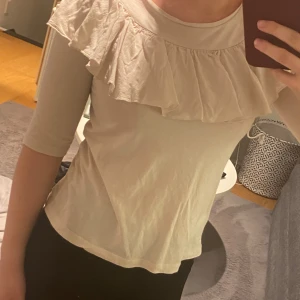 Ros/Beige topp med volang från Lindex - Säljer en söt ros/beige topp från Lindex i storlek XS. Den har trekvartsärmar och en fin volangdetalj runt halsen. Perfekt för både vardag och fest! 🌟