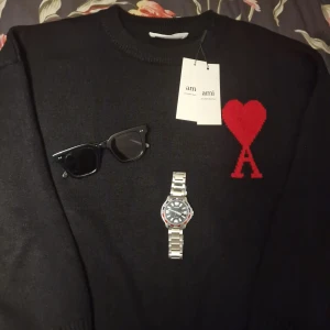  Ami Paris tröja M - Säljer en snygg svart tröja från Ami Alexandre Mattiussi med ett rött hjärta och bokstaven A på bröstet. Perfekt för en stilren look. Tröjan är i mycket bra skick och tillverkad i Portugal. Passar perfekt för höst och vinter. Den är ny med tags i nyskick. Priset kan diskuteras vid snabb äffär😊🌟