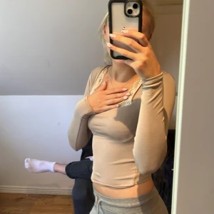 Beige långärmad topp med spetsdetaljer - Säljer en superfin beige långärmad topp. Den är tight och perfekt för både vardag och fest. Materialet känns mjukt och stretchigt, vilket gör den bekväm att bära hela dagen.