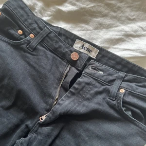 Svarta jeans från Acne - Säljer ett par svarta jeans från Acne i storlek 28/34. De är i modellen Flex S Wet Black och är low waisted. 