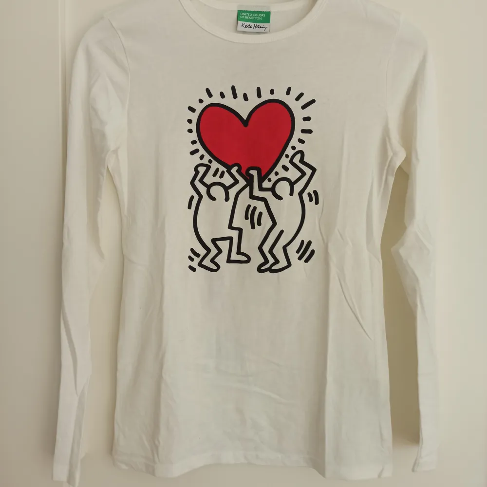 Säljer en superfin vit långärmad tröja från United Colors of Benetton med ett coolt Keith Haring-tryck på framsidan. Tröjan är i bomull och har en normal passform. Perfekt för både vardag och fest! 💖 Storlek 160. Använd högst fem gånger. . Tröjor & Koftor.