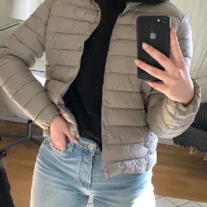 Beige pufferjacka - Säljer en snygg beige pufferjacka som är perfekt för kyliga dagar. Jackan har en croppad passform och stängs med knappar. Den är lätt och bekväm, vilket gör den idealisk för både höst och vår. Perfekt för en casual look!
