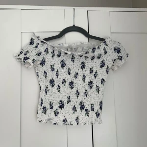 Blommig topp - Jättesöt topp från nelly i storlek S! Offshoulder. Skulle mer säga att den sitter som en XS p.g.a resåren. Köparen står för frakt 