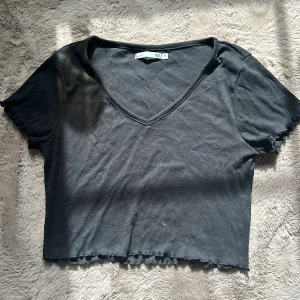 Svart topp - Svart kort topp med volanger i sömmarna. Skick 6/10