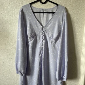 Ljusblå blommig klänning med knappar - Aldrig använd. Super fin klänning som endast säljs då modellen inte satt bra på mig!