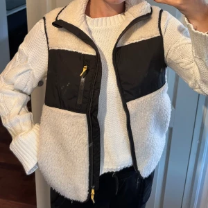 Väst - Säljer denna mysiga krämvita teddyväst med svarta detaljer och dragkedja från H&M, storlek XS, använd en gång 