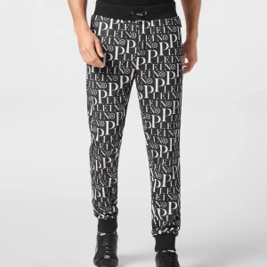 Svarta mjukisbyxor från Phillip Plein - Säljer ett par svarta Phillip Plein mjukisbyxor med en fet vit logotyp över hela tyget. De har en elastisk midja med snörning och muddar vid bensluten. Perfekta för en avslappnad stil eller chill hemma. Superbekväma och stiliga!