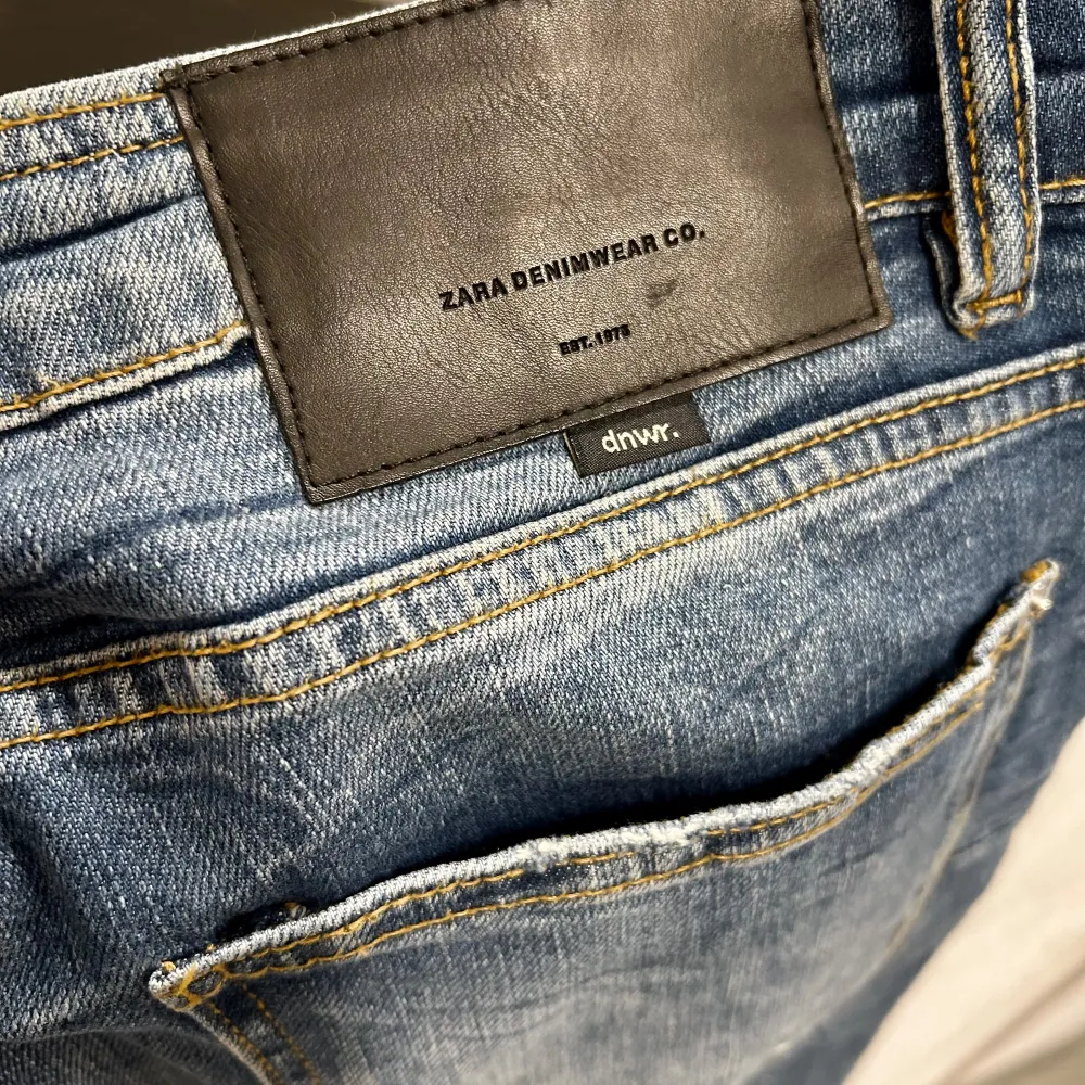 Säljer ett par snygga blå jeans från Zara Denimwear Co. med coola slitningar och färgstänk för en trendig look.  Skick 9/10. använda en gång. storlek 32/32 slim fit. Köpta på Zara för 599kr. Jeans & Byxor.