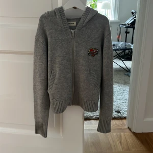 Grå zip up hoodie från Zadig & Voltaire  - Tröjan är stickad i grå och har en detalj med ett hjärta där loggan står på. Tröjan är också i mycket fint skick! Köparen står för frakt.