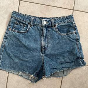 Säljer ett par snygga lågmidjade jeansshorts från H&M i storlek M. De är i en klassisk blå denimfärg med en fransig kant nertill för en avslappnad look. Shortsen har en knapp och dragkedja framtill samt fem fickor. Perfekta för sommardagar! skriv vid frågor💗