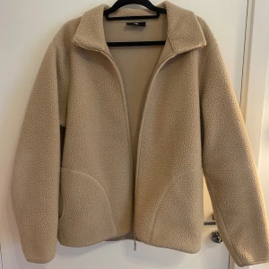 Beige teddyjacka från H&M - Säljer en supermysig beige teddyjacka från H&M i storlek L. Den har en dragkedja framtill och är perfekt för kyliga dagar. Jackan är i regular fit och passar både till vardags och lite mer avslappnade tillfällen. Den är i bra skick och väldigt bekväm att ha på sig💗