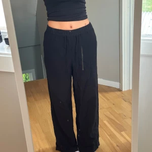 Svarta byxor med dragsko - Säljer ett par svarta linnebyxor med dragsko i midjan. De är superbekväma och har en loose passform, perfekt för en avslappnad stil. Byxorna är gjorda i ett mjukt material och har en rak siluett.