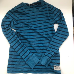 Blå randig långärmad tröja - Säljer en snygg blå långärmad tröja med svarta ränder. Perfekt för en avslappnad stil och passar bra till både jeans och kjol. Tröjan är i bra skick och superbekväm att ha på sig. Perfekt för höst och vår! Barnstorlek men ksk XS?