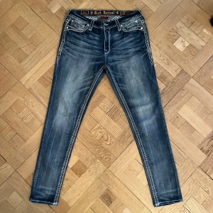 Vintage Rock Revival Jeans - De perfekta jeansen för hösten, ursnygg vintage look med fina sten- och läderdetaljer på bakfickan 🙌🤞 Storlek: W33  Mått Midja ca. 43cm  Inre benlängd ca. 77cm Yttre benlängd ca. 104cm Bredd nedtill ca. 22cm