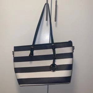 Michael Kors väska  - Äkta Michael Kors väska med gulddetalier, jättesnygg perfekt till skolan, jobbet eller resa! På tredje bilden syns storleken jämfört med ett A4 format. 