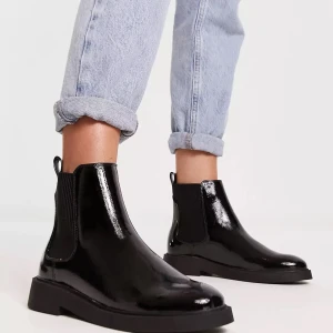 Svarta blanka boots - Ett par snygga svarta blanka boots i skinn. De har en stilren design med elastiska paneler på sidorna för enkel på- och avtagning. Perfekta för både vardag och fest!
