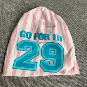 Randig vit å rosa med 29 på den och en blå text som det står go for it - Den e randig med en blå text och blå 29 storlek 52-54