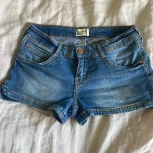 Säljer ett par snygga blå jeansshorts från Perfect Jeans i storlek 36. De har en klassisk femficksdesign med knapp och dragkedja framtill. Perfekta för sommardagar eller utflykt. De är i bra skick och redo för nya äventyr! 