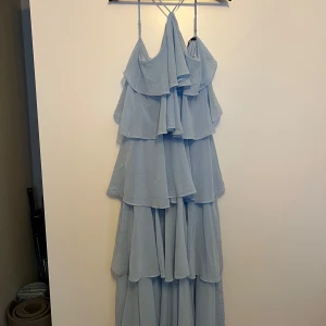 Lång klänning - Blå lång klänning med volanger från Gina tricot. Använd 1 gång.