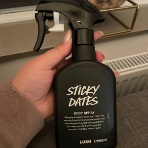 Sticky Dates Body Spray från Lush - Sticky Dates Body Spray från Lush i en svart sprayflaska på 200 ml. Doften är en kombination av benzoin, resinoid och sandelträ, vilket ger en söt och varm arom. Perfekt för den som älskar en rik och inbjudande doft.