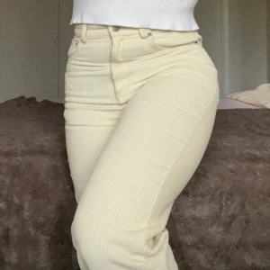 Beige manchesterbyxor från Gina Tricot - Snygga beige manchesterbyxor från Gina Tricot i storlek 34. Byxorna har en hög midja och en rak passform med dragkedja och knapp framtill. Perfekta för en stilren look.