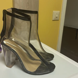 Transparenta klackskor med dragkedja - Snygga transparenta klackskor med svart kant och dragkedja bak. Skorna har en unik design med genomskinlig klack och öppen tå. Perfekta för att göra ett statement.