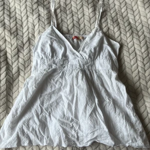 Gullig vit topp - Jätte gullig vit topp, med snören att knyta på baksidan. Kuporna är ganska små. Säljer eftersom den inte kommer till användning. Inga defekter. PRIS GÅR ATT DISKUTERA