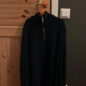 Svart stickad tröja från Zara - Säljer en svart stickad tröja från Zara med dragkedja vid halsen. Tröjan har en hög krage och långa ärmar, perfekt för kyligare dagar. Enkel och stilren design som passar till det mesta.