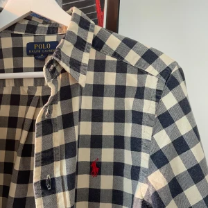 Rutig skjorta från Ralph Lauren - Snygg rutig skjorta från Ralph Lauren i blått och vitt. Skjortan är sällsynt och perfekt för vardagen och festligare sammanhang. Storleken sitter som S. Tveka inte på att höra av er kring frågor!😁