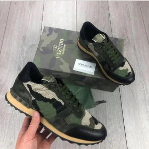 Valentino Rockrunner i camouflage - Snygga Valentino Rockrunner sneakers i ett coolt camouflage-mönster. Skorna har en kombination av gröna och svarta nyanser med en beige sula. Perfekta för en trendig look.