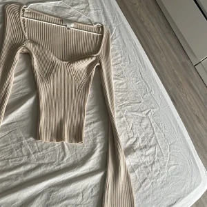 Beige ribbad topp från H&M - Snygg beige ribbad topp från H&M med långa ärmar och en elegant fyrkantig halsringning. Perfekt för en stilren look.