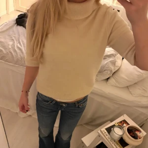 Beige stickad polotröja - Säljer en mysig beige stickad polotröja med trekvartsärm. Perfekt för kyligare dagar och ger en stilren look. Passar bra till jeans eller kjol.