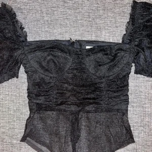 Svart glittrig bodysuit - Snygg svart glittrig bodysuit med puffiga kortärmar och dragkedja bak. Perfekt för en kväll ute eller nyår! Storlek s, uk8. Passar även xs. Aldrig använd, lappar kvar. Kom gärna med prisförslag om du är intresserad✨