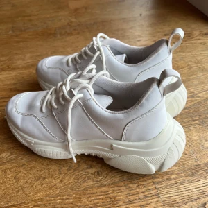 Vita sneakers med snörning - Snygga vita sneakers från Nelly med chunky sula och snörning. Perfekta för en stilren look. Skorna har en modern design med en bekväm passform.