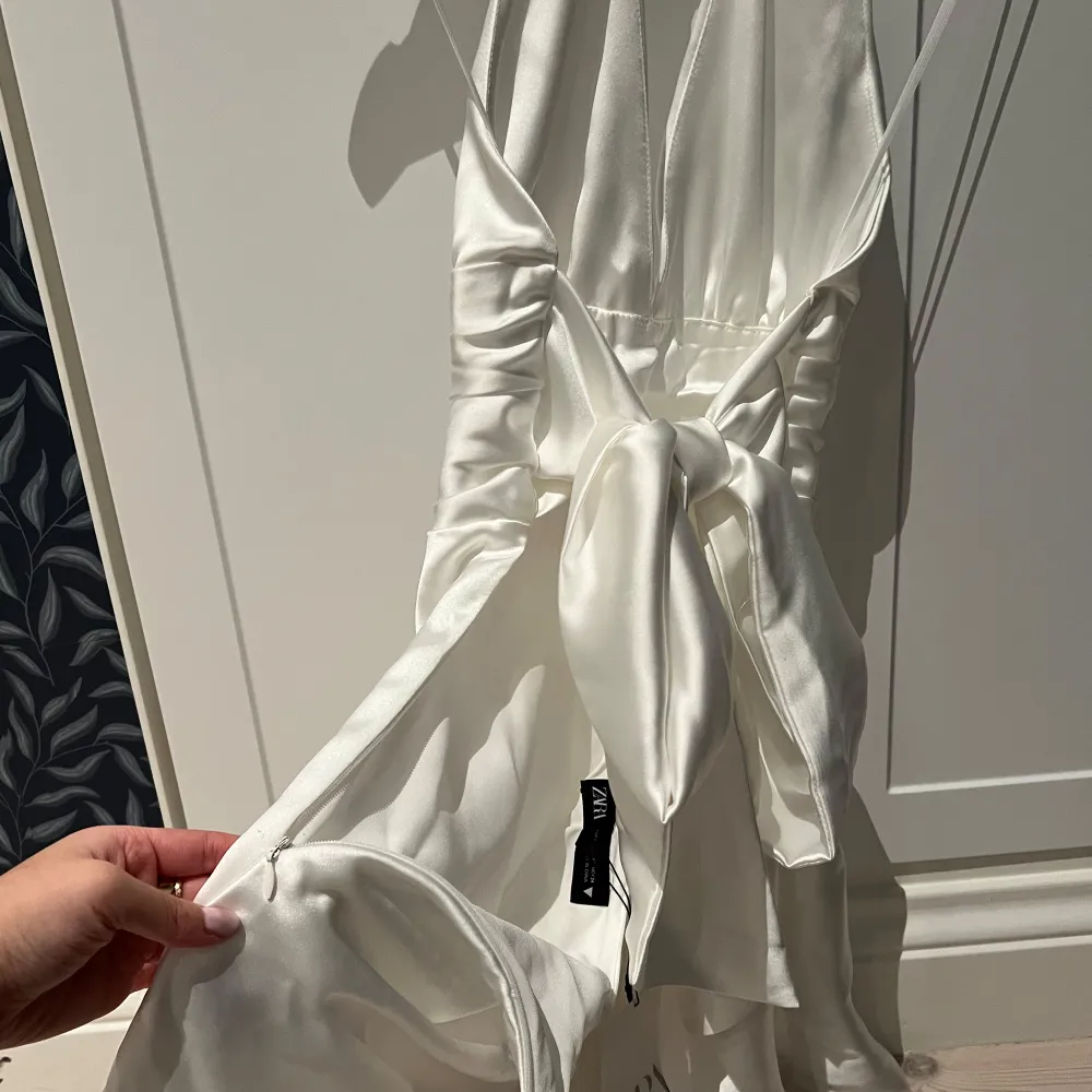 Superfin vit halterneck klänning från Zara i satin🤍Knytband i midjan som inte bara är fina utan också gör det enkelt att ändra hur tajt klänningen ska sitta. Väldigt diskret och smidig dragkedja på sidan🎀 Säljer för att den inte riktigt passar mig över bysten. Endast provad och lappen kvar😇 Storlek XS🌸. Mekot.