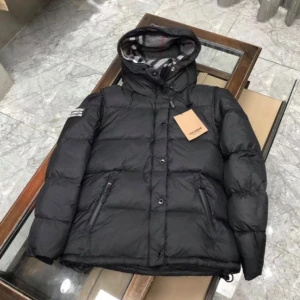 Svart dunjacka från Burberry - Snygg svart dunjacka från Burberry med rutig insida i svart, vitt och rött. Jackan har en huva och dragkedja framtill samt en Burberry-logga på ärmen. Perfekt för kyliga dagar. Storlekar: M, L, XL, 2XL, 3XL, 4XL och 5XL