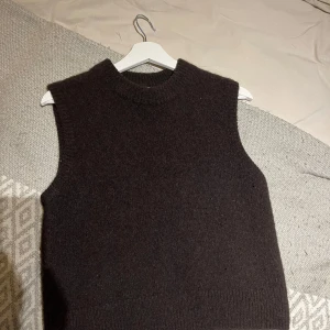 Brun stickad väst - Säljer en stilren brun stickad väst med rund halsringning. Perfekt för lager-på-lager under kyligare dagar. Enkel och tidlös design som passar till det mesta! Från arket, använd fåtal gånger. Nypris 700 kr