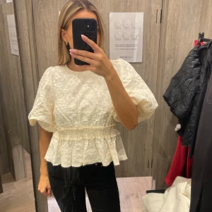 Vit blus med volangdetaljer - Säljer denna superfina blus som är köpt nyligen och endast använd 1 gång till ett dop, men kommer inte komma till någon mer användning. Nypris är 699 Den ser lite gul ut på första bilden men de är bara ljuset 🥰