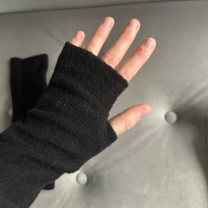 Svarta fingerlösa handskar - Säljer ett par svarta fingerlösa handskar som är perfekta för kyliga dagar. De är mjuka och bekväma, vilket gör dem idealiska för att hålla händerna varma samtidigt som du kan använda dina fingrar fritt.