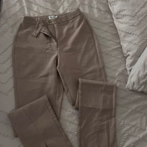 Beige byxor med dragkedja - Snygga beige byxor med dragkedja och knapp framtill. De har en stilren design med raka ben och en hög midja. Perfekta för en chic och avslappnad look.