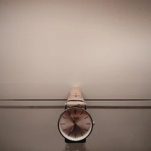 Elegant klocka från Regal - Stilren klocka från Regal med en silverfärgad urtavla och smala svarta visare. Klockan har ett beige armband med krokodilpräglat mönster som ger en lyxig känsla. Perfekt för en minimalistisk stil.