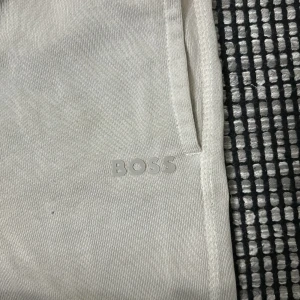 Grå mjukisbyxor från Boss - Snygga och bekväma grå mjukisbyxor från Boss med elastisk midja och muddar vid bensluten. Perfekta för en avslappnad stil. Diskret logotyp på sidan.