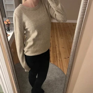 Stickad tröja/sweterek z dzianiny - Säljer en mysig beige stickad tröja med rund halsringning. Tröjan har långa ärmar och en klassisk passform, perfekt för kyligare dagar. Passar bra till både jeans och kjol.