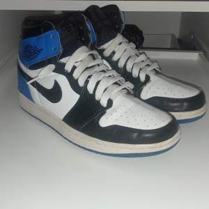 Snygga Nike Air Jordans i en klassisk färgkombination av svart, vit och blå. Skorna har snörning och en hög design som ger bra stöd. Perfekta för både stil och komfort.
