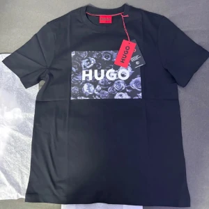 Svart t-shirt från Hugo - Snygg svart t-shirt från Hugo med ett blommigt mönster och logotyp på bröstet. Perfekt för en stilren look.