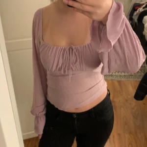 Ljuslila topp från Gina Tricot - Säljer en söt ljuslila topp från Gina Tricot med långa ärmar och knytning framtill. Köparen betalar för frakten!!!