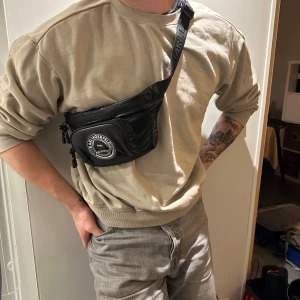 Svart magväska från Karl Lagerfeld - Snygg svart magväska från Karl Lagerfeldt. Stiligt sätt att bära nödvändiga saker med en märkeslogga framtill (KL). Annars helt utsåld - NYPRIS - 2200kr (väskan är helt oanvänd!)